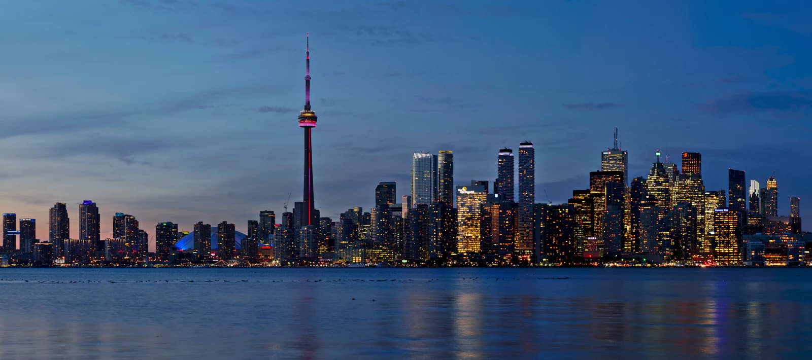 Toronto skyline at dusk beside Lake Ontario